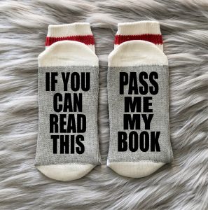 Socks with the scripts "If you can read this" and "Pass me my book" written on the bottoms, witty gifts for book lovers.