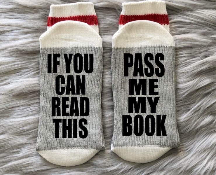 Socks with the scripts "If you can read this" and "Pass me my book" written on the bottoms, witty gifts for book lovers.