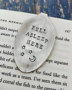Flattened silver spoon turned into a clip-on bookmark that says "Fell Asleep Here" with moon and stars.