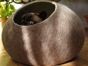 Wool cat bed with walls and a small hole opening.