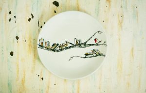 Ceramic plate with illustrated books perched on a branch with a bird.