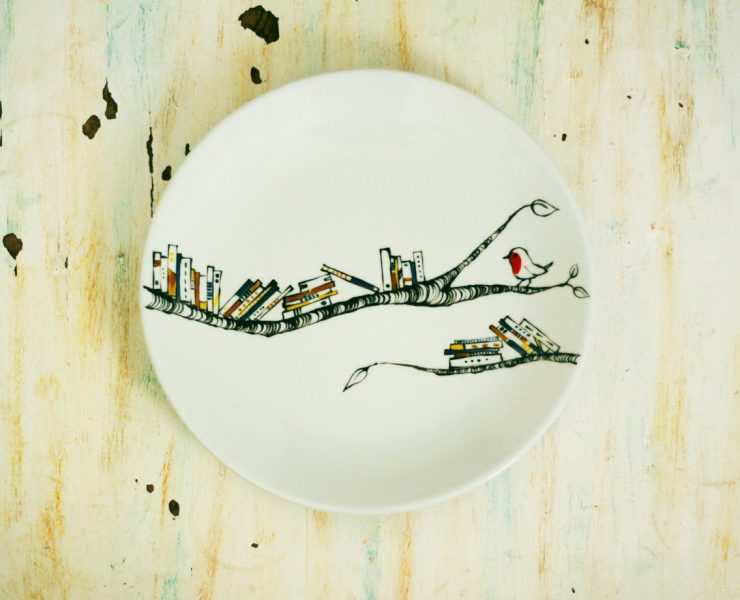 Ceramic plate with illustrated books perched on a branch with a bird.