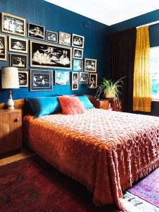 A bedroom that steals the show with its blue wallpaper, vintage pictures, and antique-inspired bedding.