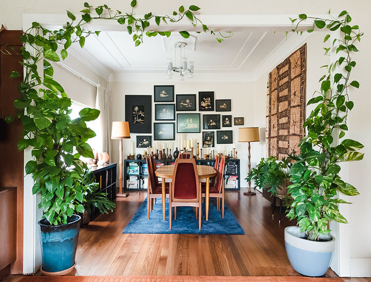 A dining room fueled by vintage collectibles, antique pictures, and maroon-plated furniture.