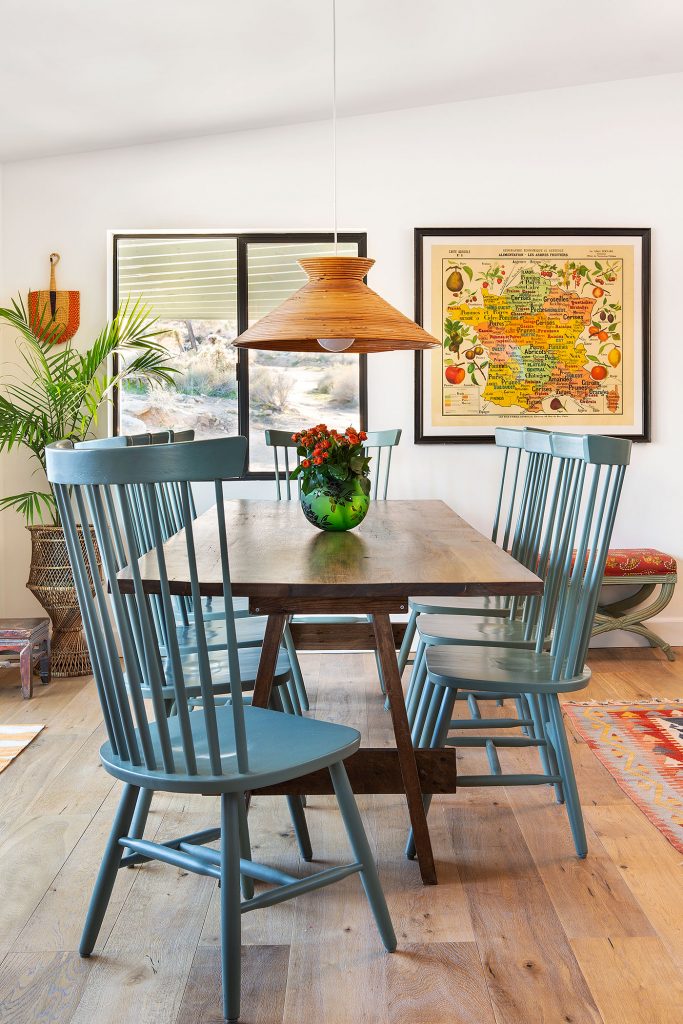 A moroccan-style kitchen that houses woven fans and blue chairs that complement its sleek wooden tabletop.