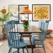 A moroccan home renovation highlighting the dining room's woven fans and blue chairs that complement a sleek wooden tabletop.