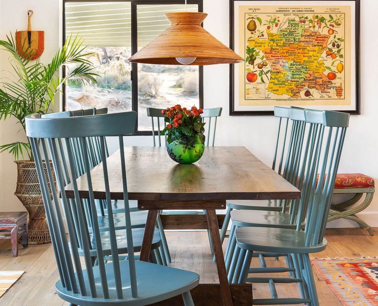 A moroccan home renovation highlighting the dining room's woven fans and blue chairs that complement a sleek wooden tabletop.
