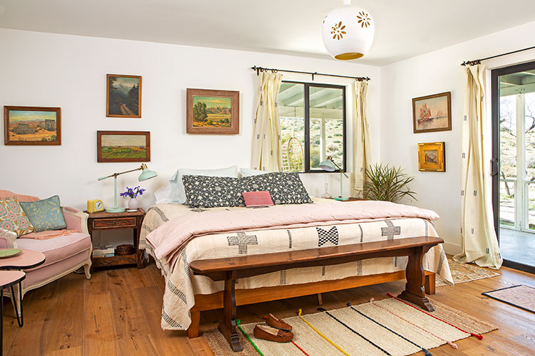 A moroccan-inspired renovation focused on a chic bed frame with pink sheets and reclaimed wood tabletop directly next to it.