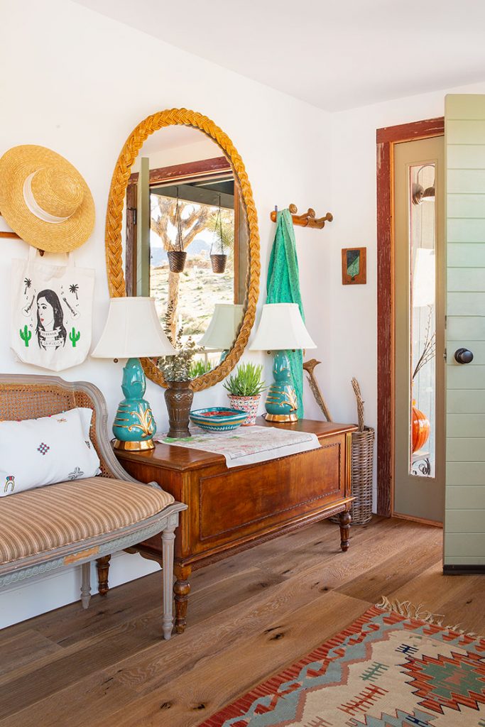 An entryway with blue lamps, an oval mirror, and other reclaimed pieces.