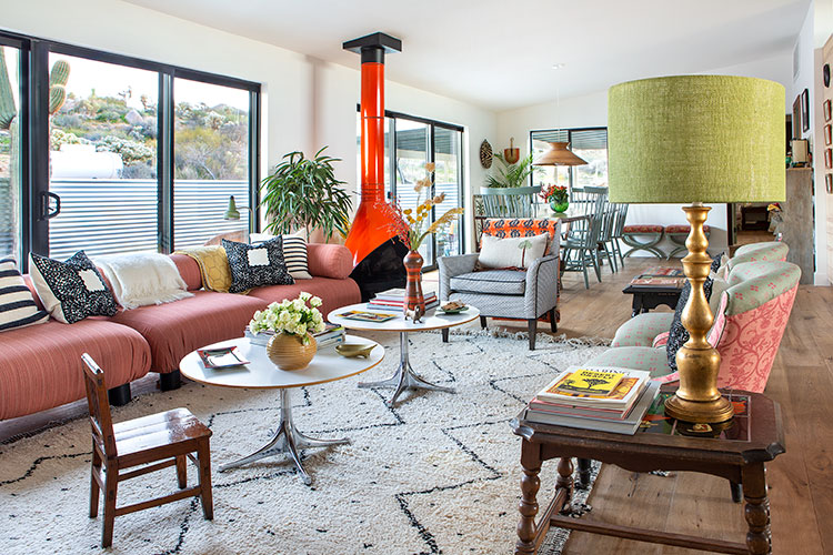 A moroccan-inspired living room that features woven pillows and a fluted fireplace.