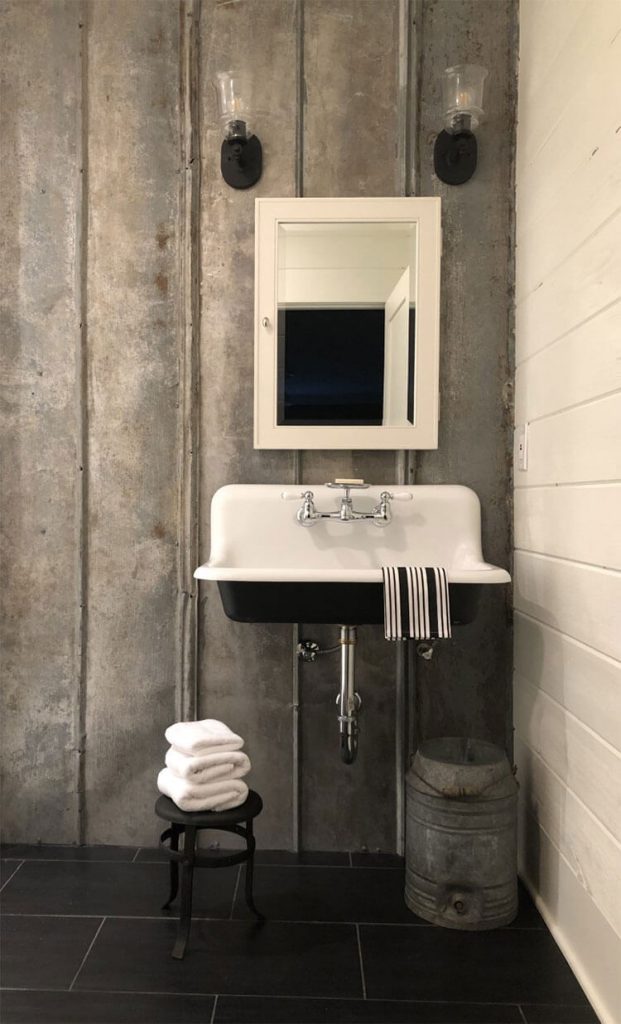 A bathroom, complete with a metal-based wall scheme, vintage milk stool, and white fixtures.