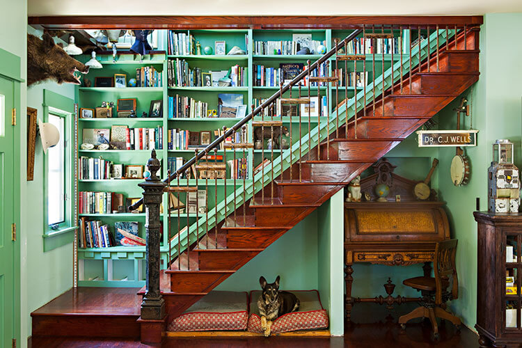 A rustic renovation featuring a wooden, open staircase with a dog resting beneath it.