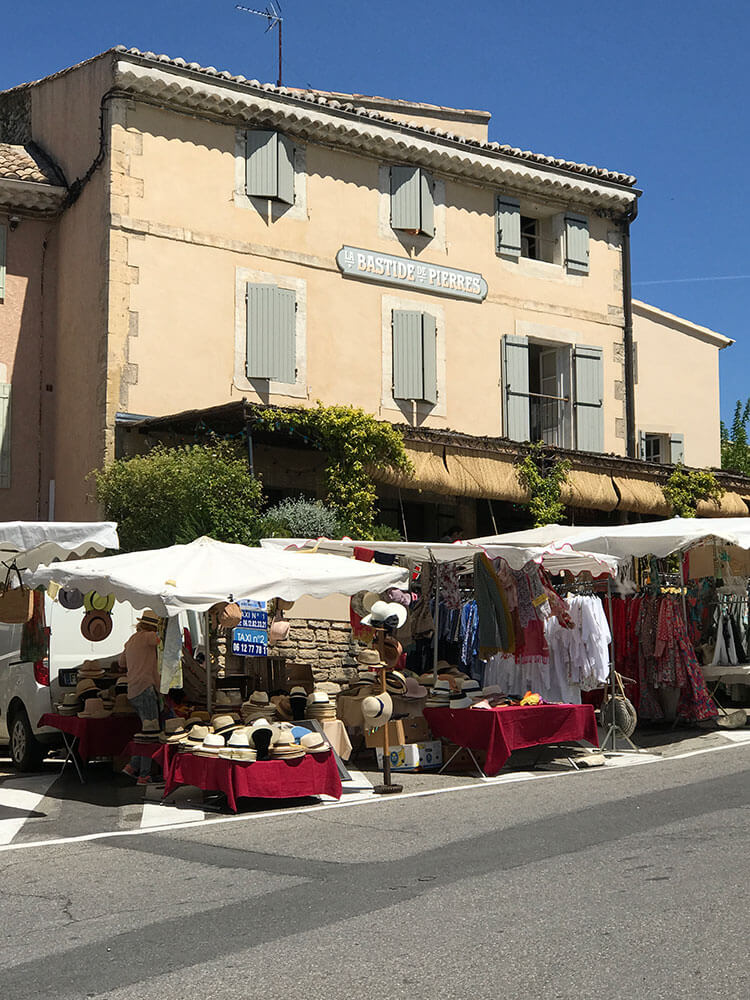 A flea market spotlighting white awnings and red tables covered in antiques.