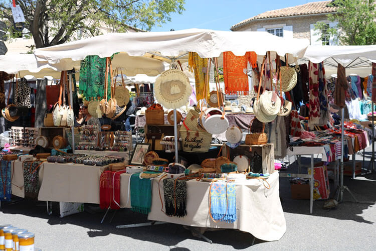Vendor stand with a white awning and several pieces of antique clothing for sale.