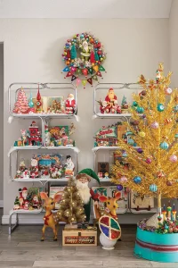 gold faux tree with bright vintage ornaments in front of shelves with vintage figurines