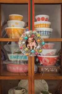 colorful wreath with reindeer at the center in front of hutch with vintage Pyrex