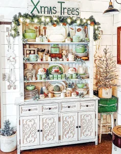 hutch decorated for Christmas with garland, dried oranges and Santa mugs