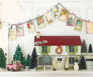 garland of Christmas cards above small wooden house and toy vintage truck