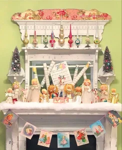 mantel with vintage choir figurines and top shelf decorated with Shiny Brite tree topper ornaments