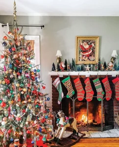 Christmas tree with colorful ornaments and vintage stockings and framed vintage Santa art