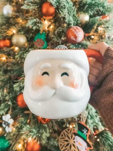 smiling Santa mug in front of decorated Christmas tree