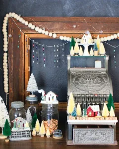 antique cash register decorated for Christmas with mini bottlebrush trees