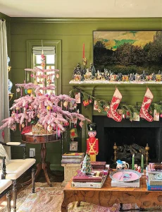 mantel with mini Christmas village flanked by nutcracker and pink mini tree with tinsel