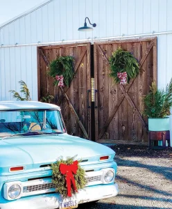 barn doors with holiday cedar wreaths and classic truck with wreath on bumper