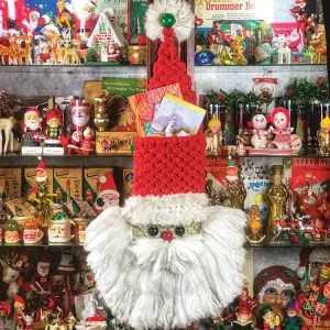 crocheted Santa holiday card holder in shelf with collections of Santa mugs, vintage elf, reindeer and snowman figurines