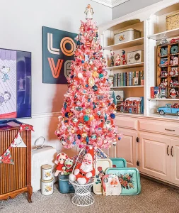 pink artificial tree with bright ornaments and vintage serving trays and Muppet stuffed animals