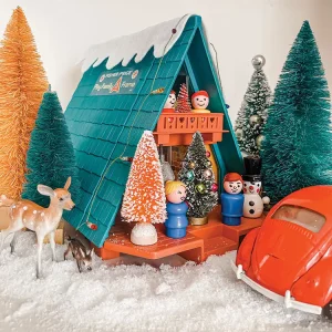 A-frame toy house with fake snow, toy VW bug and bottlebrush tree