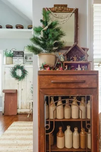 modern collected farmhouse with hallway vignette with mini Christmas house and potted pine tree