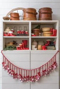 Santa boot collection layered into pantry shelving with garland of red and white knit socks
