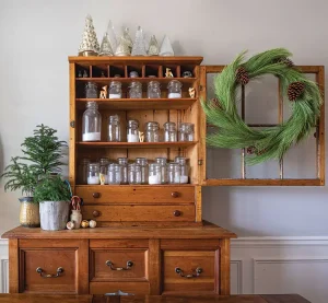 pine wreath on cabinet displaying glass trees and small deer figurines