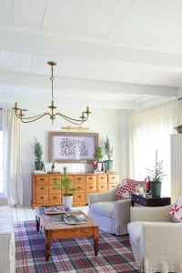 sitting area with plaid rug and framed Merry Christmas sign and red and white throw pillows