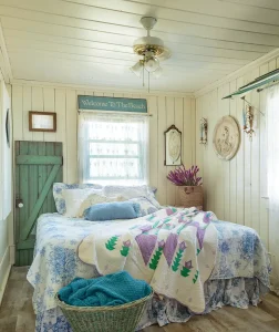 bedroom with white and blue bedspread and white cream beadboard walls in cottage by the bay