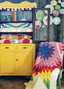 vintage quilts collected in a yellow hutch